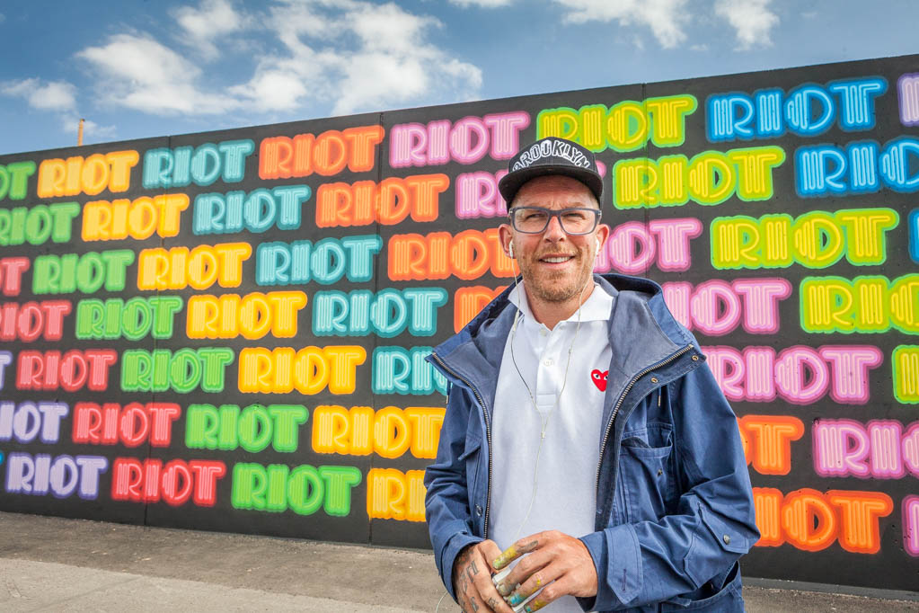 Artist Ben Eine in front of a colorful mural