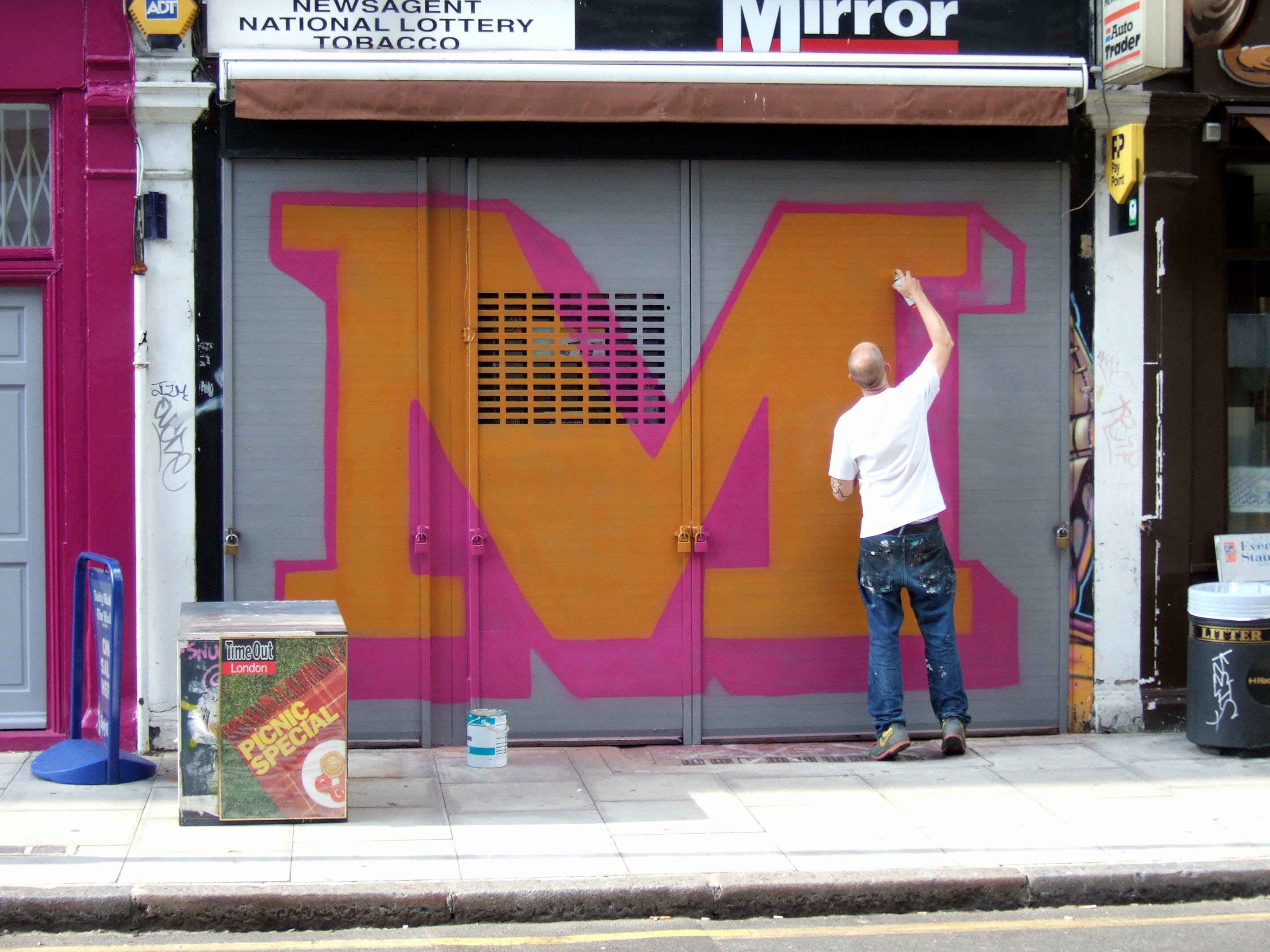Artist Ben Eine spray-painting a mural of the letter "M"