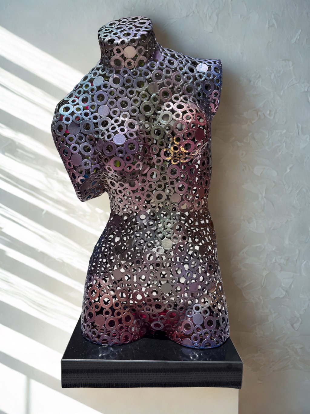 Ayden Snider Forged in Circles: Openwork female torso formed from welded metal washers on a dark rectangular base.