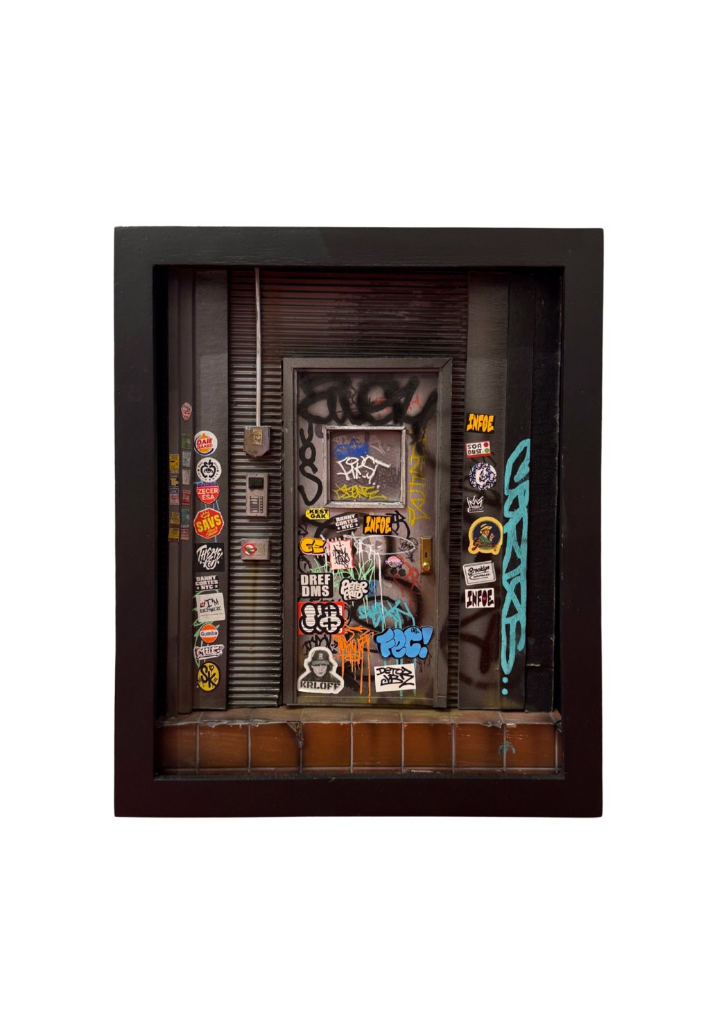 Danny Cortes Brooklyn Door Series: miniature sticker-covered doorway with graffiti, ribbed walls, and a tiled base in a black frame.