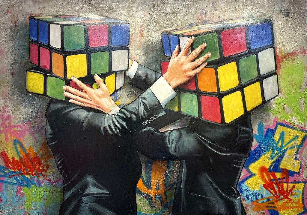 Hijack Puzzled: two suited figures with colorful puzzle-cube heads reach toward each other against a graffiti-covered background.