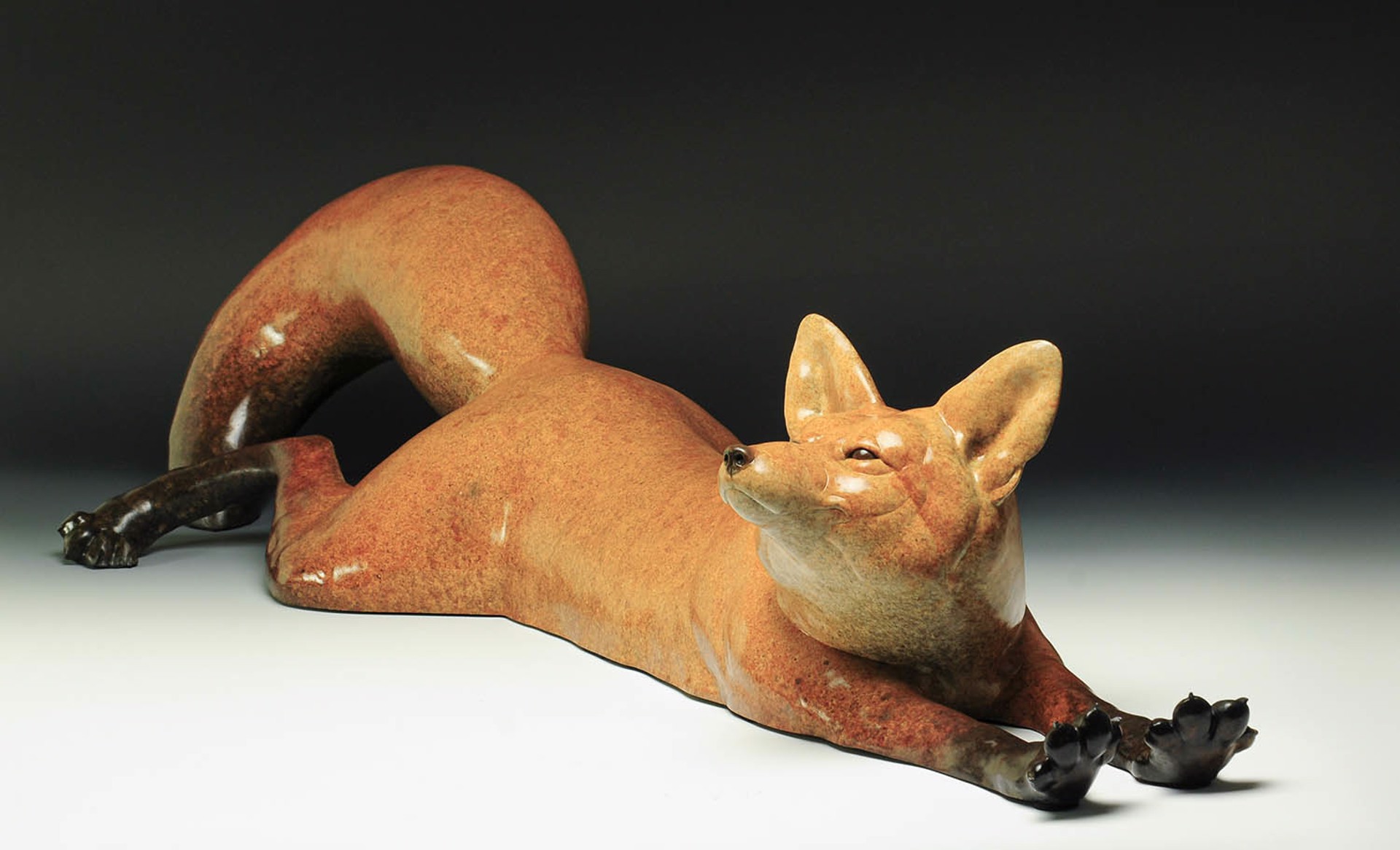 A Bronze Sculpture Of A Red Fox Stretched Out On Its Belly Featuring A Smooth Surface With A Contemporary Patina, By Jeremy Bradshaw, Available At Gallery Wild