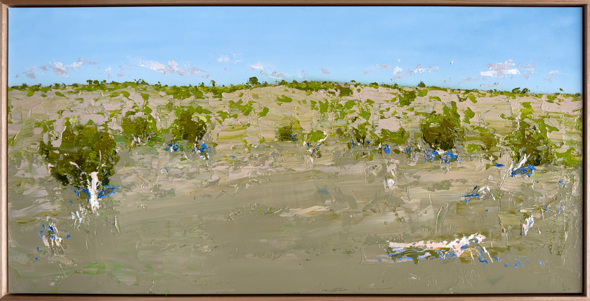 Rectangular plein air landscape painting of a gently sloping field in green shades, with shading in deep blue. A soft baby blue sky with distant cloud tufts tops of the whole picture.
