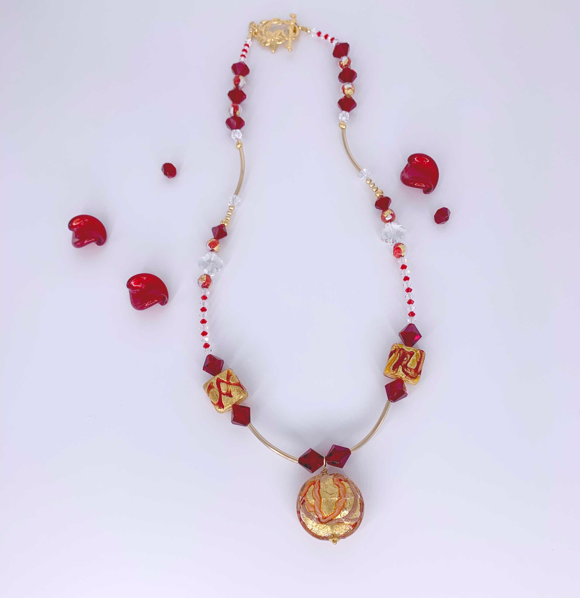 A dazzling red and gold necklace using handmade Venetian glass beads purchased in Murano, Italy, accompanied by Swarovski crystals and gold tube beads and clasp.