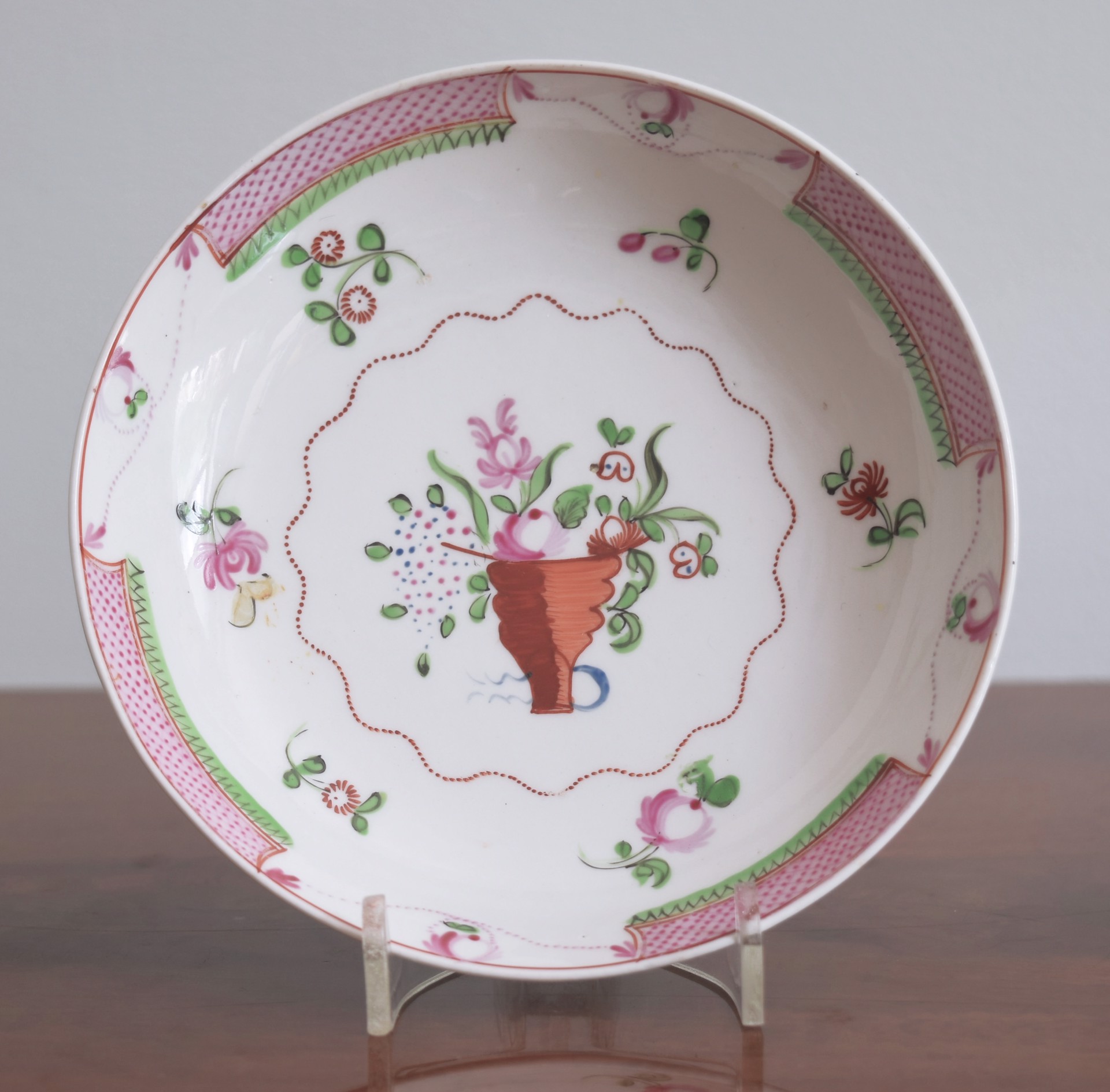A BARBED FAMILLE ROSE SAUCER WITH FLORAL CORNUCOPIA