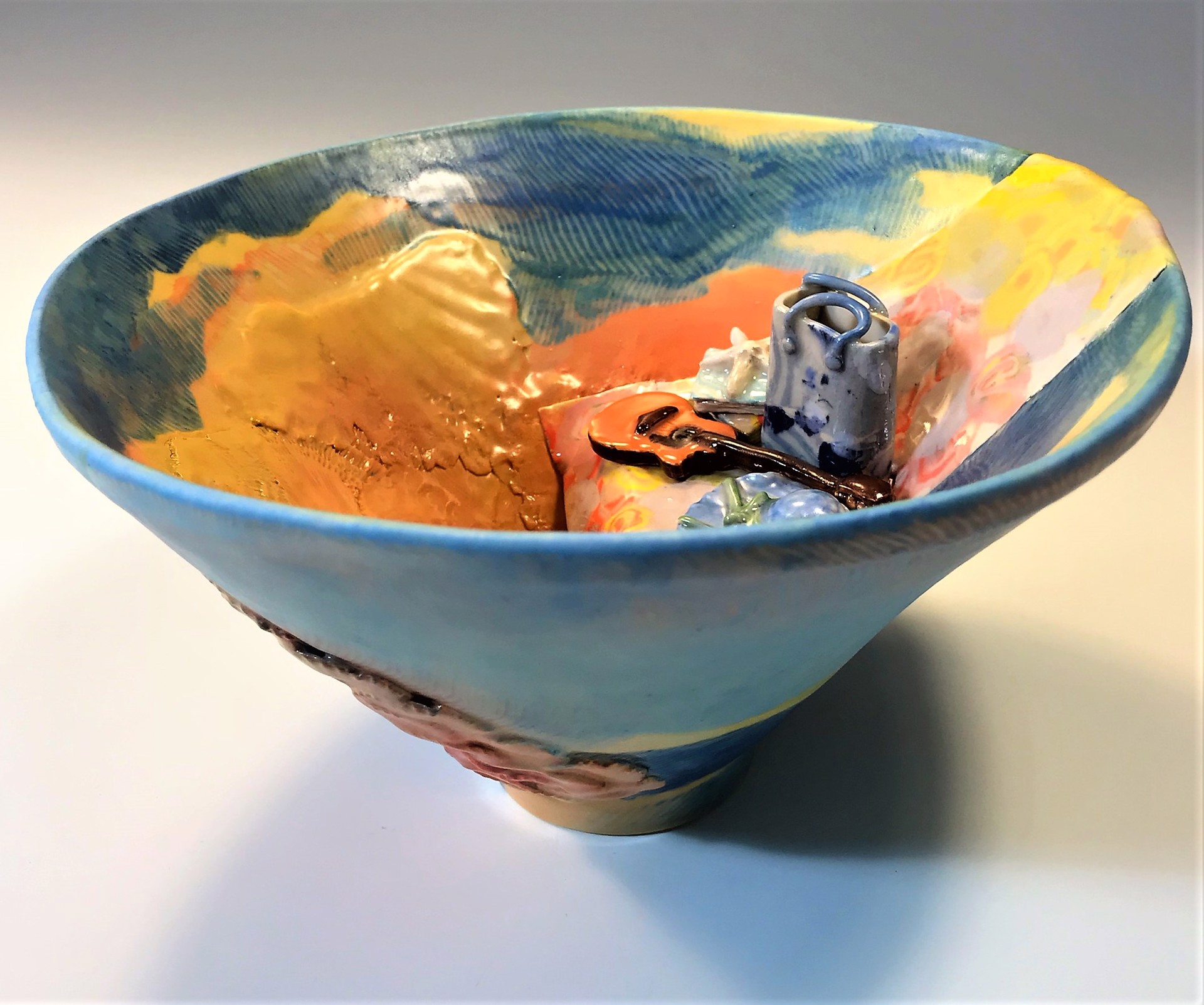 decorative bowl with a guitar and seat on the inside, blue and orange colors