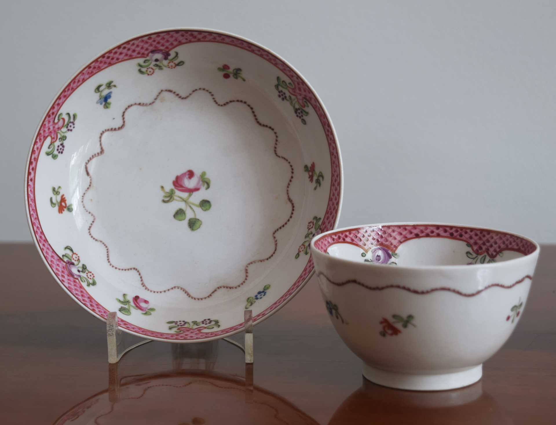 A FAMILLE-ROSE TEACUP AND SAUCER WITH LATTICE RIMS