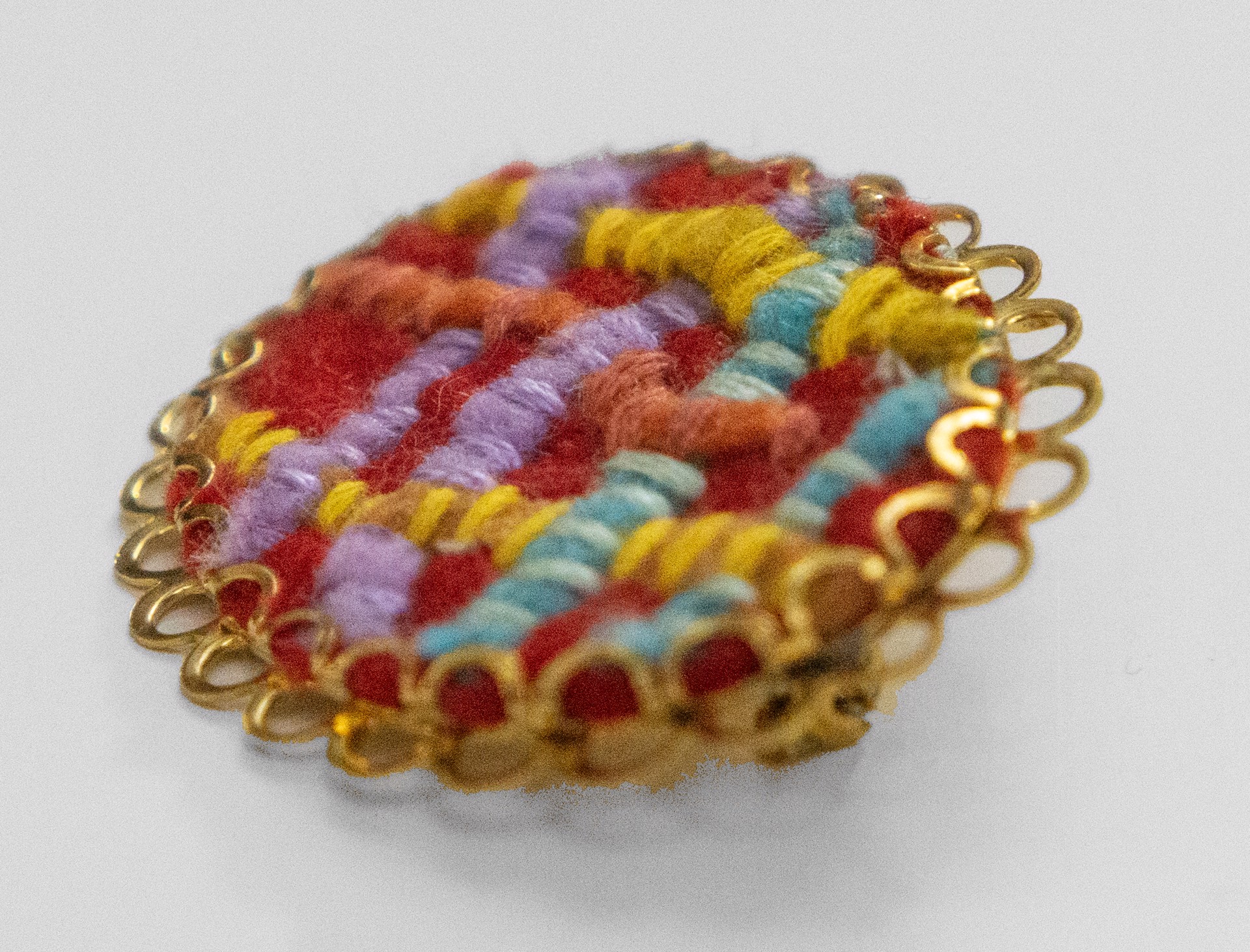 Red abstract woven brooch by Hattie Lee Mendoza