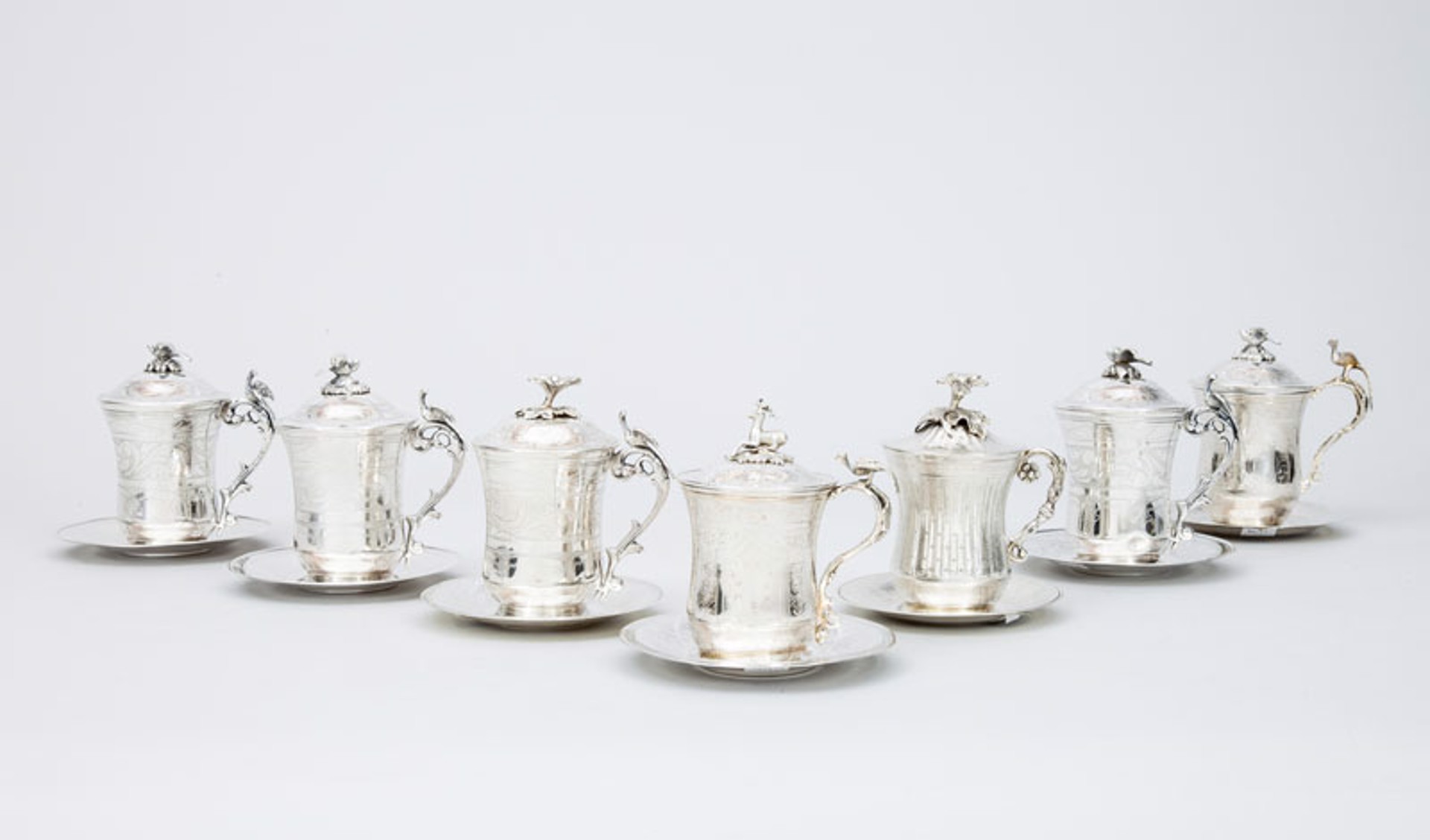 GROUP OF SEVEN STERLING SILVER TANKARDS WITH LIDS AND SAUCERS