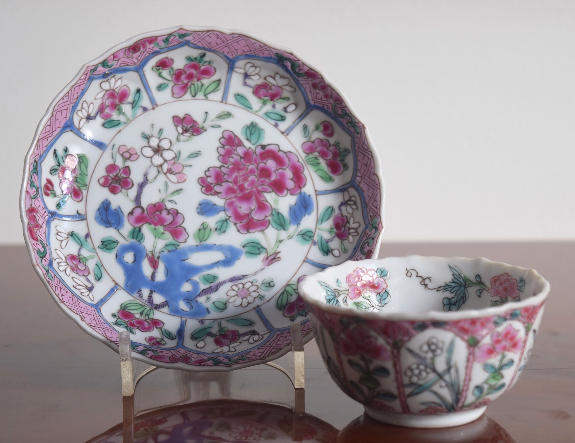 FAMILLE ROSE TEACUP AND SAUCER WITH CENTRAL FLOWER, 10 RESERVES, BLUE CELL AND PINK DIAMOND DIAPER BORDER