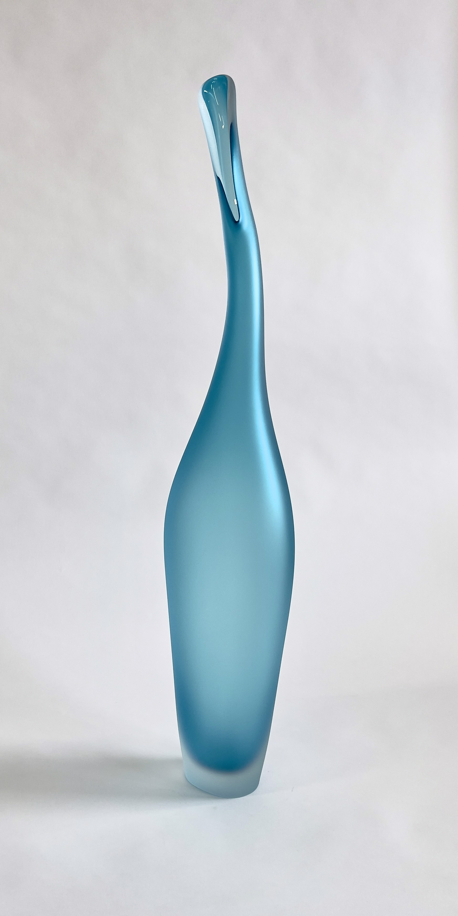 Copper Blue Lima by The Goodman Studio is a tall, slender glass sculpture in a shade of light blue. The sculpture is sandblasted but has hints of transparency.