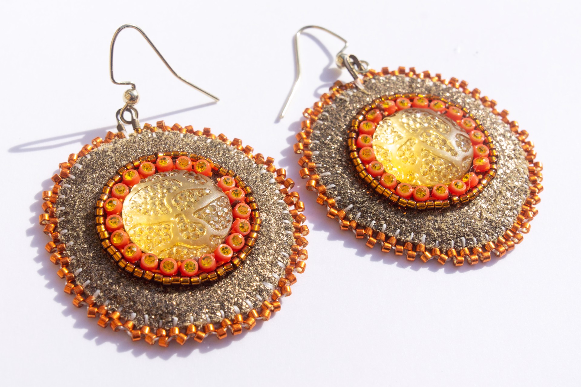 Gold and orange earrings by Hattie Lee Mendoza