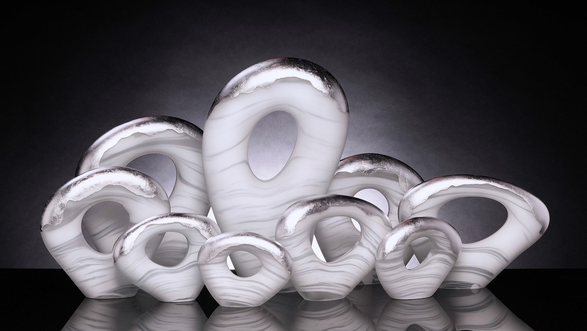 Silver Thoughts by Florida glass artist Rick Eggert is a beautiful nine piece set of hand blown glass with whisps of white pigment and silver leaf on the top.