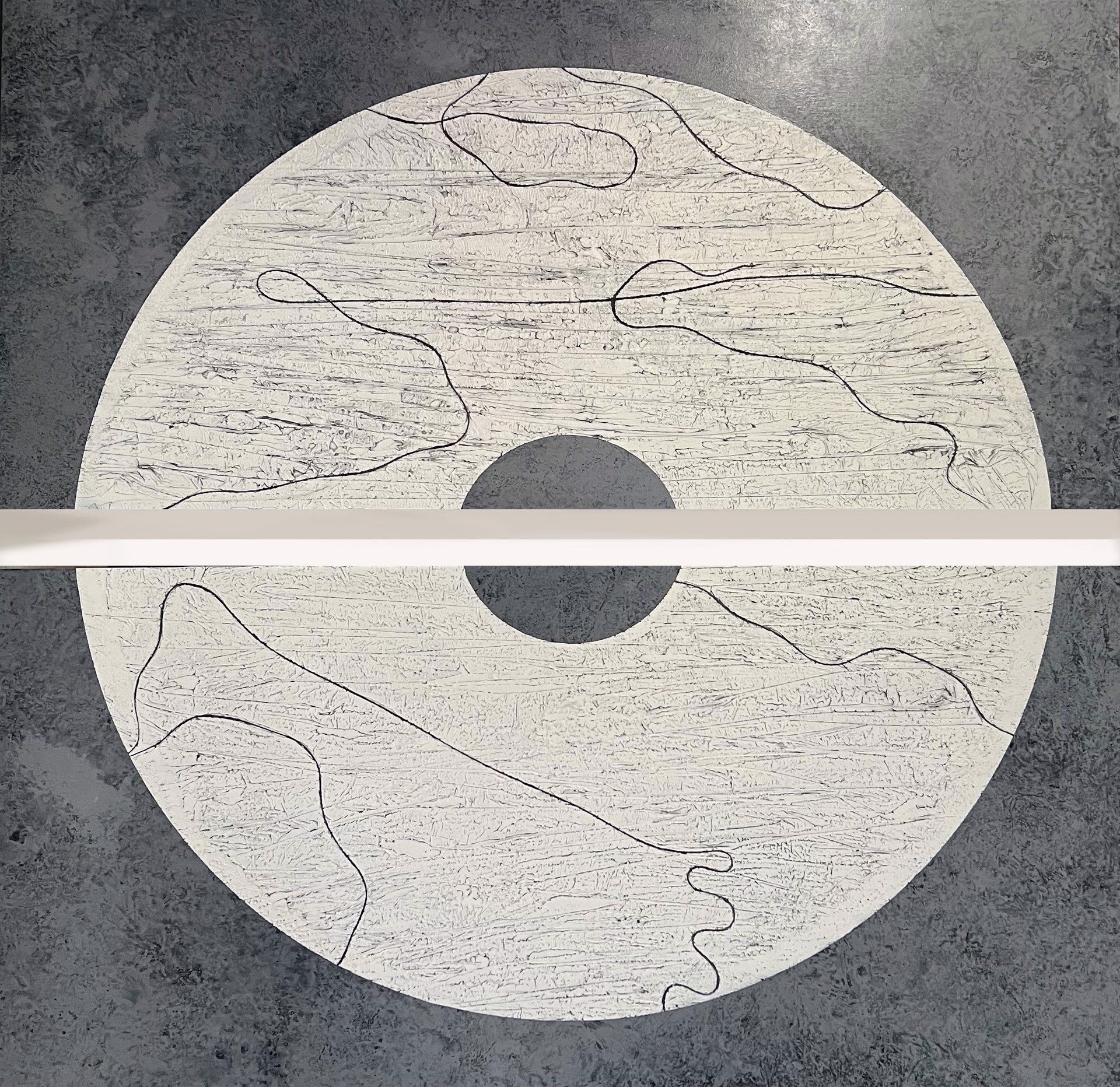 California artist and painter Stephanie Paige's 60"H x 60"W painting Consciousness is a beautiful diptych made of two wood panels with layers of grey marble plaster paint and features a white circle with gray striations and lines. 