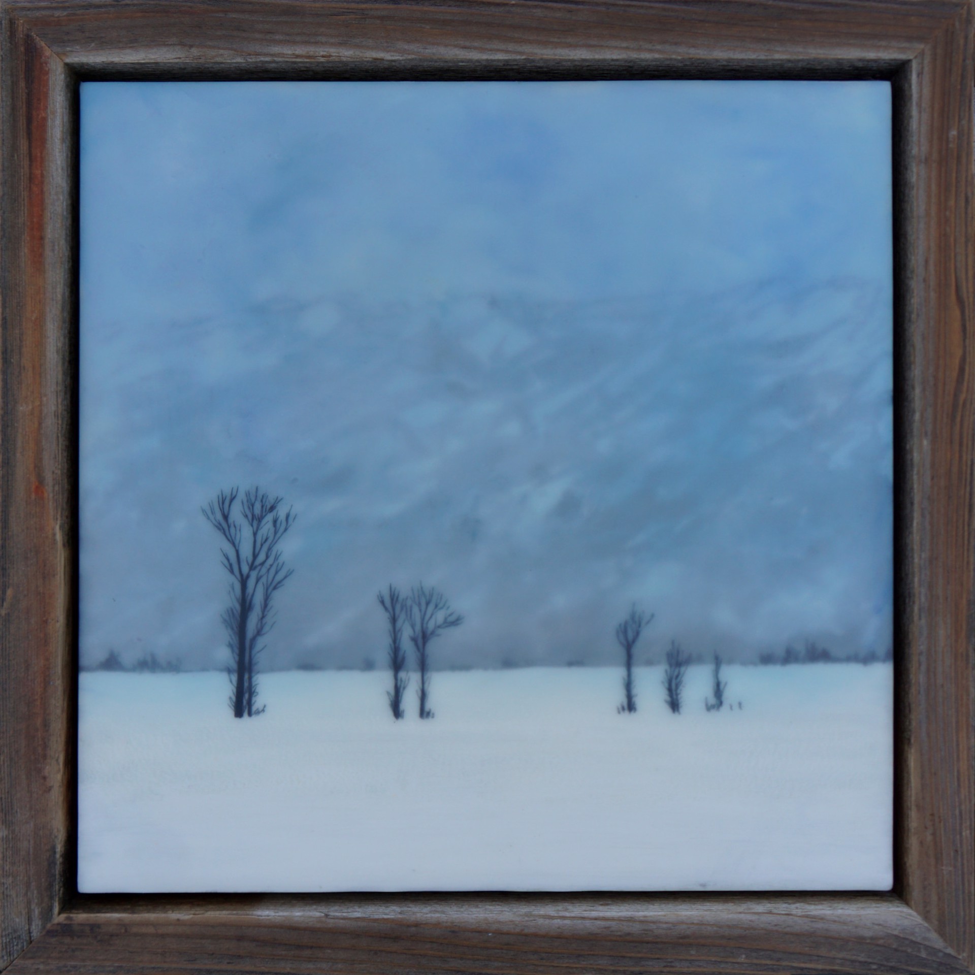 An Original Encaustic And Milk Paint Painting Of A Snow covered Landscape With Four Tree Silhouettes And A Misty Treed Hill In The Background , By Bridgette Meinhold