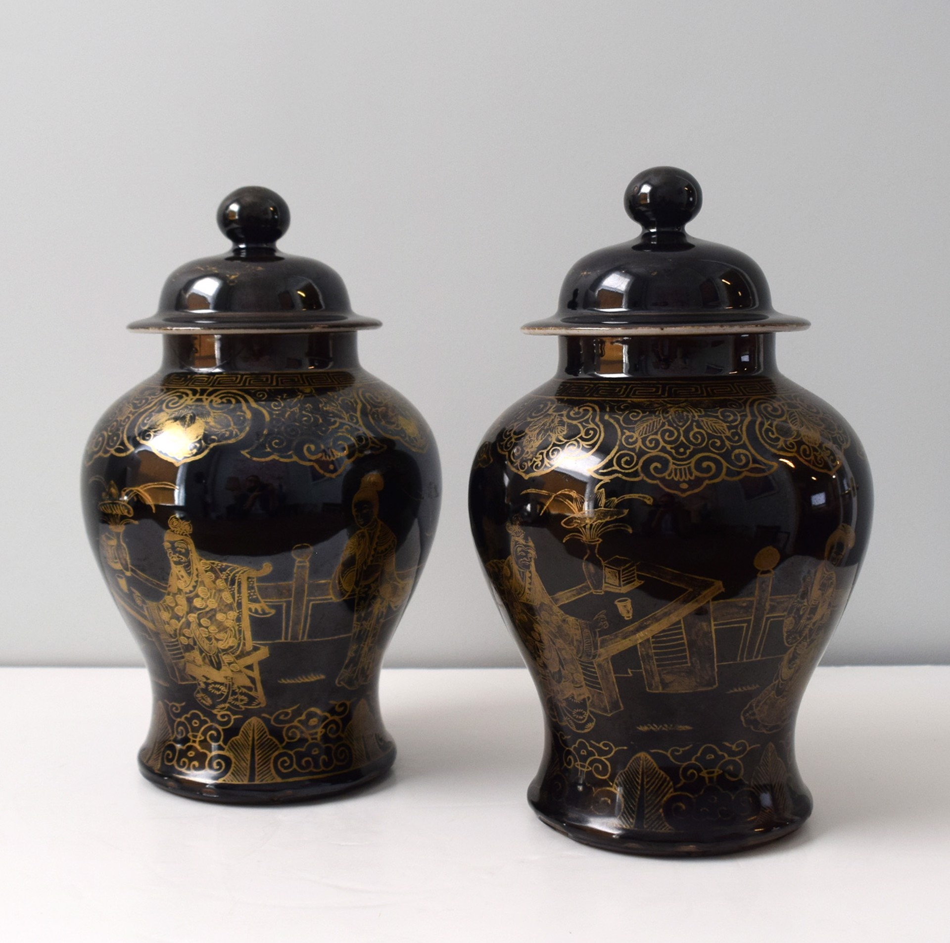 PAIR OF BLACK GROUND AND GILT BALUSTER JARS AND COVERS WITH FIGURES