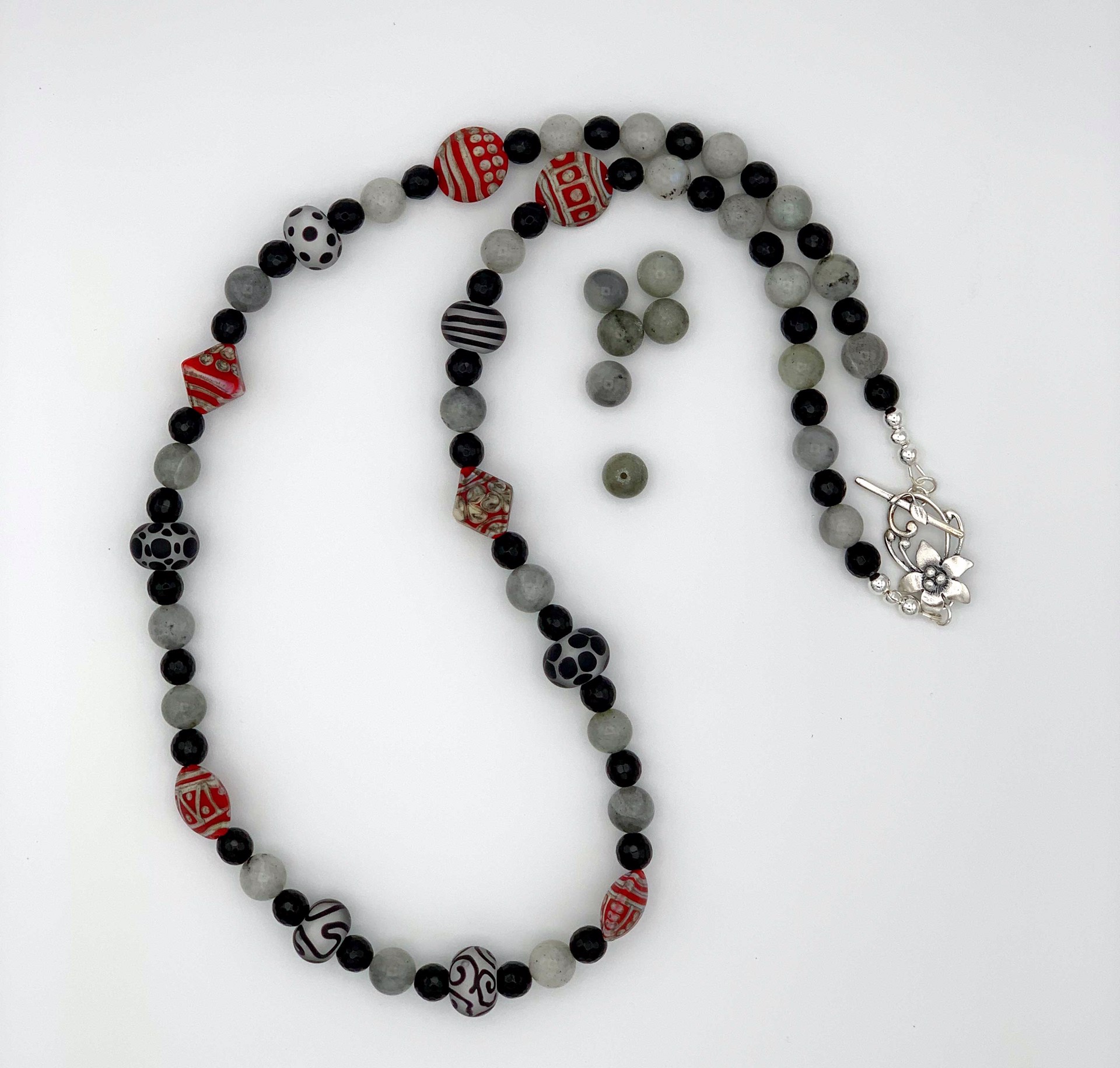 Semi-precious gemstone beads of Labradorite from Northeastern Canada and faceted Onyx add depth and class to the hand-torched glass focal beads.