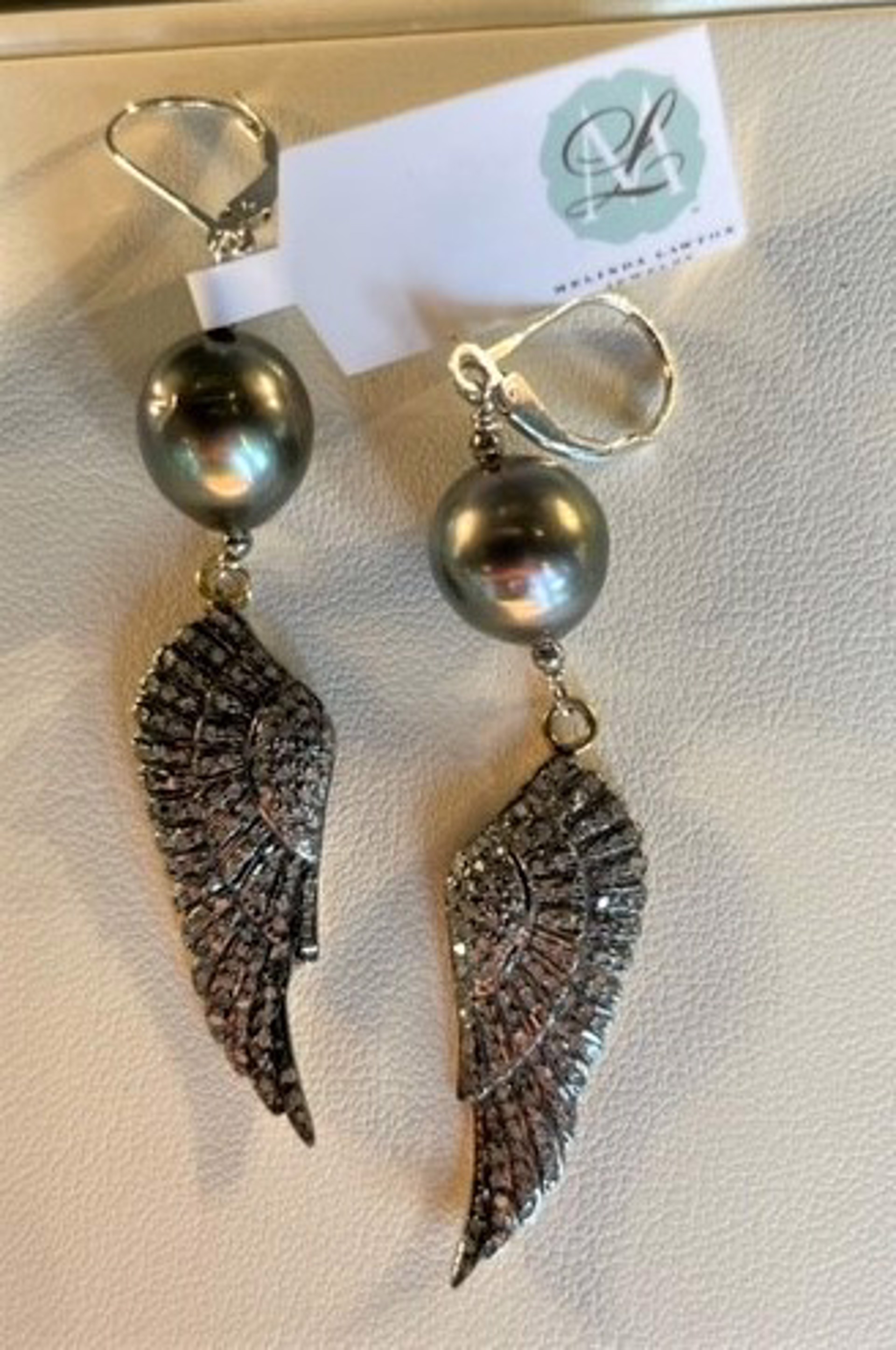 Pave diamonds in oxidized sterling angel wings hanging from Tahitian pearls in sterling silver by Melinda Lawton Jewelry