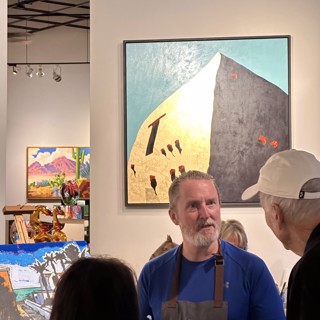 An artist speaks with visitors in front of a striking geometric painting. An artist speaks with visitors in front of a striking geometric painting.