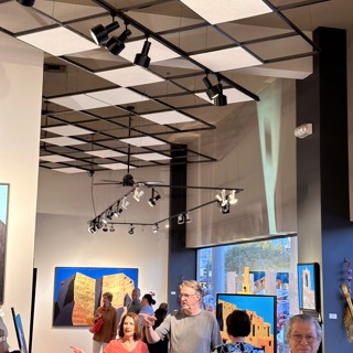 Guests engage in conversations while viewing colorful artwork in a well-lit gallery. Guests engage in conversations while viewing colorful artwork in a well-lit gallery.